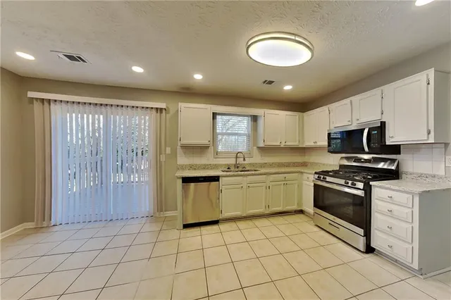 a kitchen with stainless steel appliances granite countertop a stove sink and cabinets