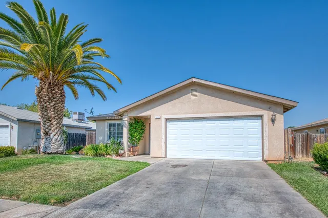 a view of a house with a yard and palm trees
