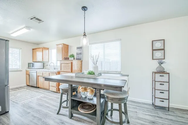 a kitchen with stainless steel appliances granite countertop a table chairs and wooden floor