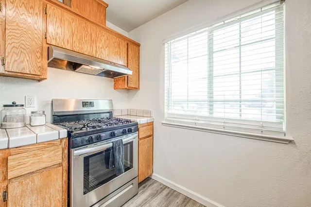 a kitchen with stainless steel appliances granite countertop a stove and a white cabinet