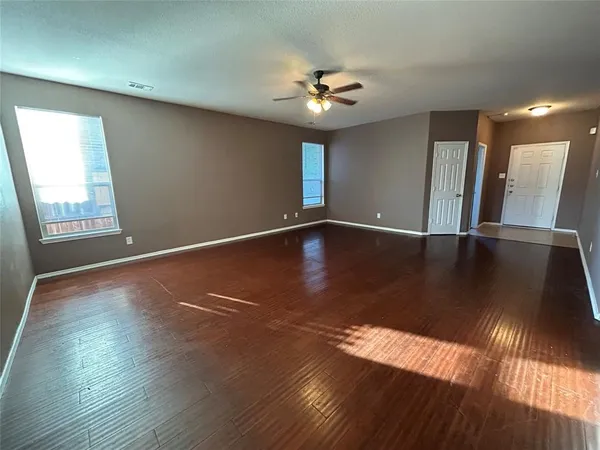 a view of an empty room with window and wooden floor