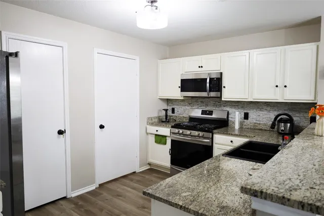 a kitchen with stainless steel appliances granite countertop a stove top oven a sink and a granite counter tops