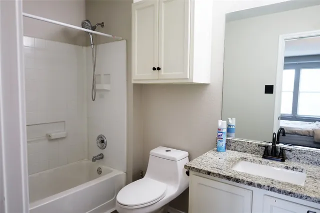 a bathroom with a granite countertop sink a toilet and shower