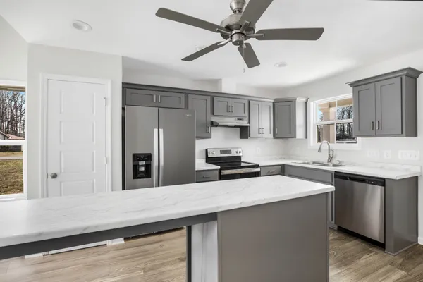 a kitchen with stainless steel appliances a sink a stove a refrigerator cabinets and wooden floor