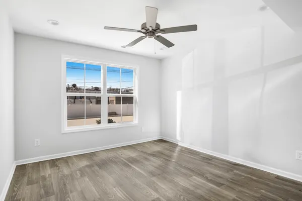 a view of an empty room with a window and wooden floor