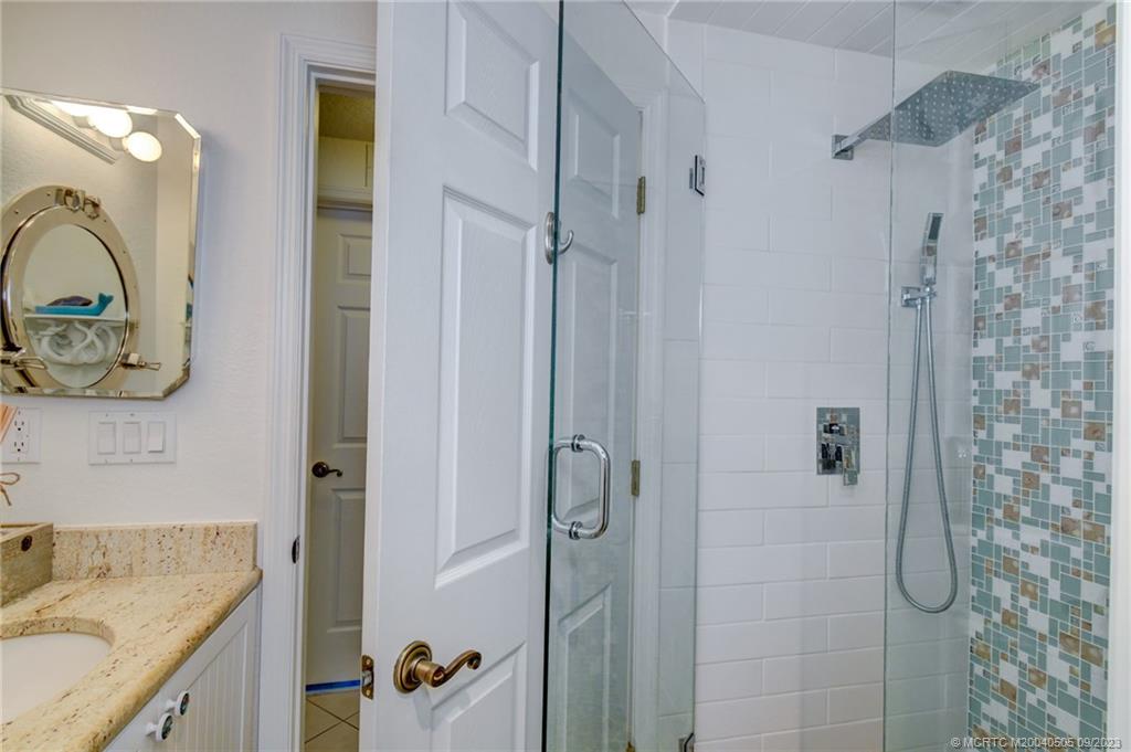 3541 Northeast Ocean Boulevard, Unit 19 Stuart, FL 34996 - Photo 24 of 52 a bathroom with a granite countertop shower sink vanity and mirror