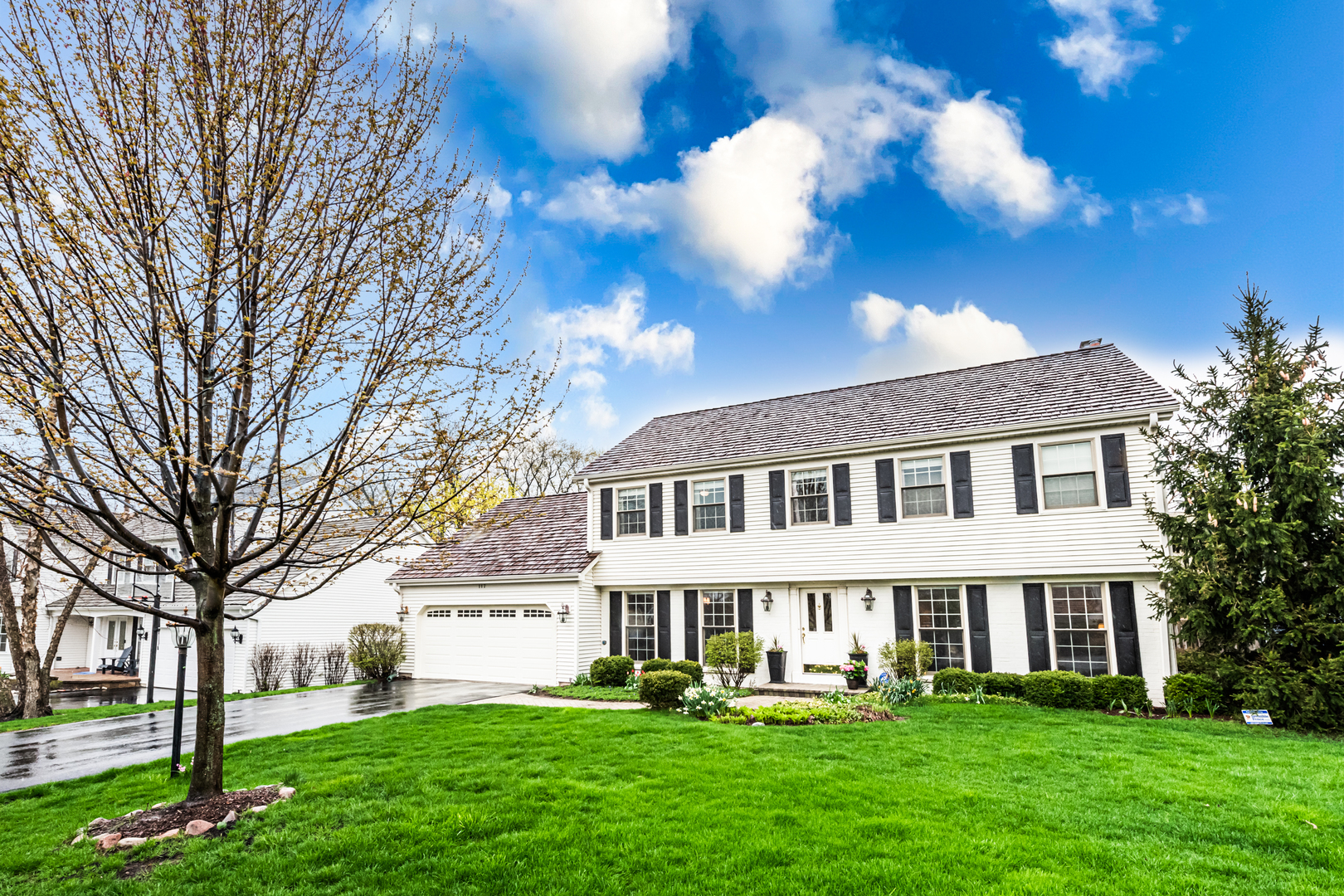 a front view of a house with garden and trees