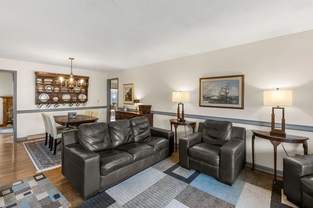 a living room with couches a dining table and chairs with wooden floor