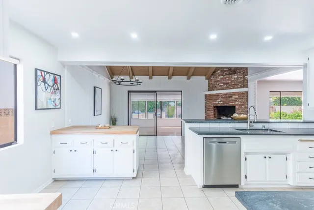 a dining hall with stainless steel appliances kitchen island granite countertop a table chairs in it and a window