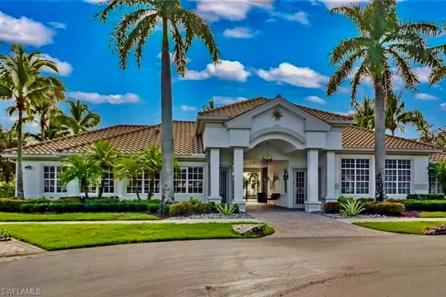 a view of a house with a yard and palm trees