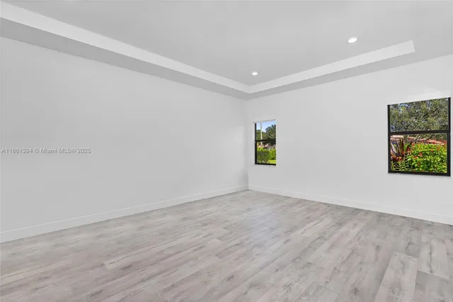 a view of an empty room with window and wooden floor