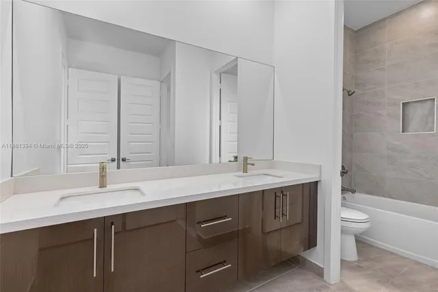a bathroom with a double vanity sink and mirror with toilet