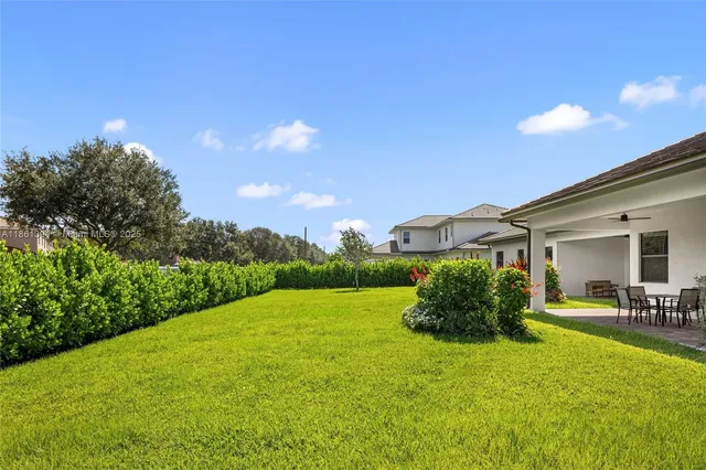 a backyard of a house with table and chairs plants and large tree