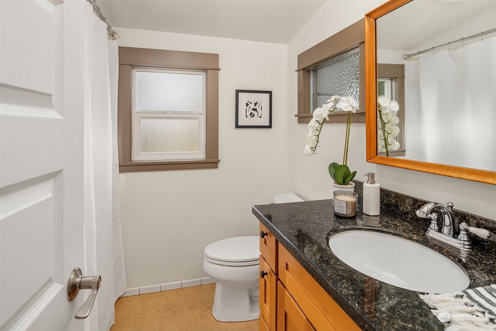 8752 Evanston Avenue North Seattle, WA 98103 - Photo 22 of 29 a bathroom with a granite countertop toilet sink and mirror