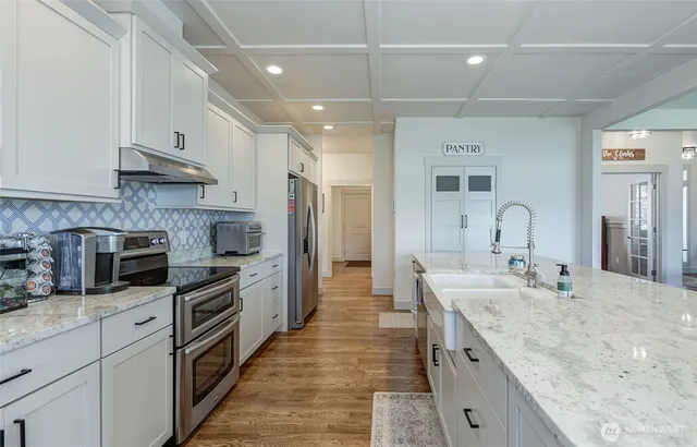a large kitchen with stainless steel appliances granite countertop a sink stove and refrigerator
