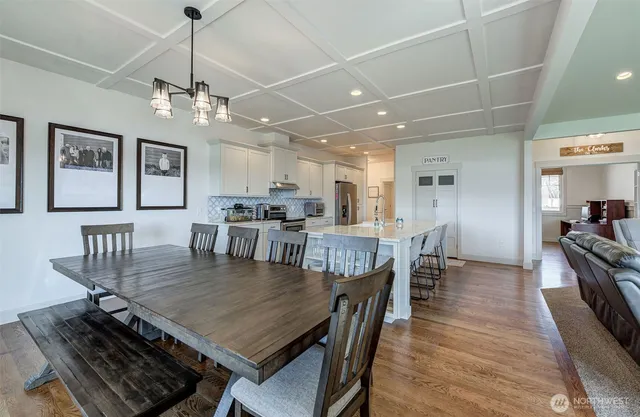 a dining room with wooden floor a chandelier a wooden table and chairs