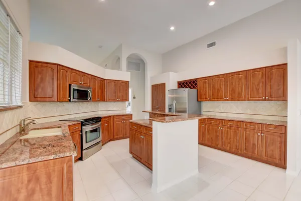 a kitchen with stainless steel appliances granite countertop a stove top oven a sink dishwasher and a refrigerator with wooden cabinets