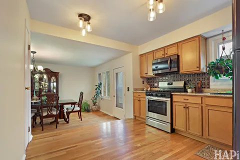 a kitchen with stainless steel appliances granite countertop a stove top oven a sink a dining table and chairs with wooden floor