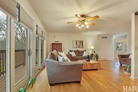 a living room with couches a fireplace and a dining table with wooden floor