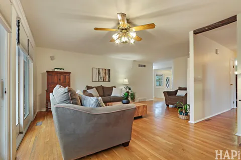 a living room with couches a coffee table and a chandelier with wooden floor