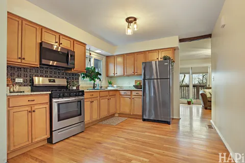a kitchen with a refrigerator stove and wooden floor