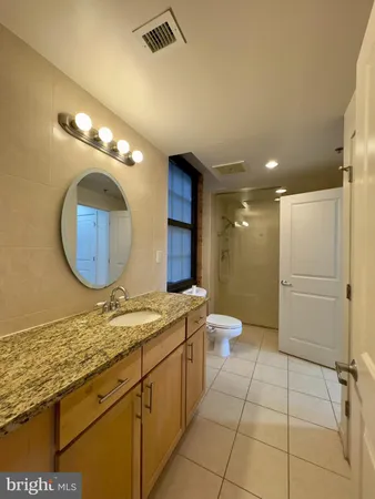 a bathroom with a granite countertop sink a toilet and a mirror
