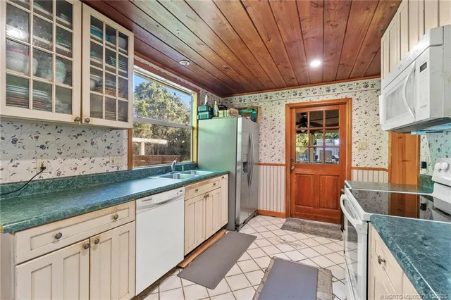 a kitchen with stainless steel appliances kitchen island granite countertop a refrigerator a stove a dining table and chairs with wooden floor