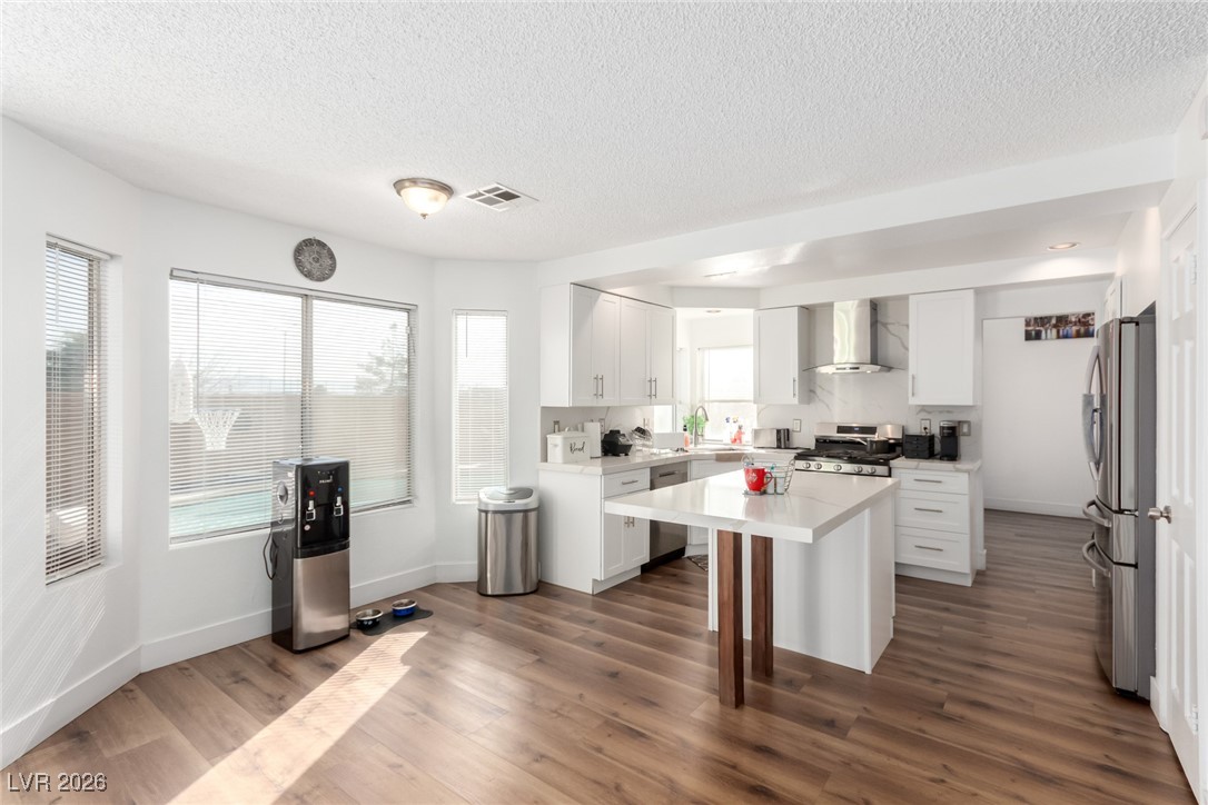 906 Ambusher Street Henderson, NV 89014 - Photo 11 of 38 Kitchen featuring white cabinetry, stainless steel appliances, a kitchen island, dark wood-style flooring, and a textured ceiling