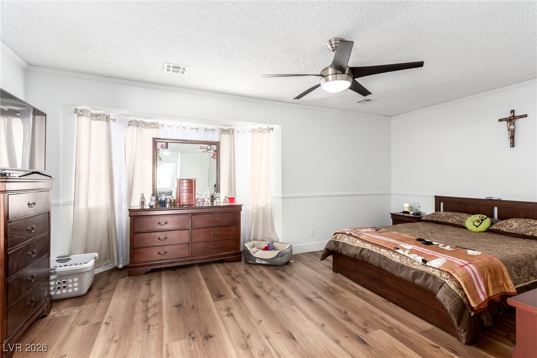 906 Ambusher Street Henderson, NV 89014 - Photo 13 of 38 Bedroom with wood-type flooring, a ceiling fan, a textured ceiling, and crown molding