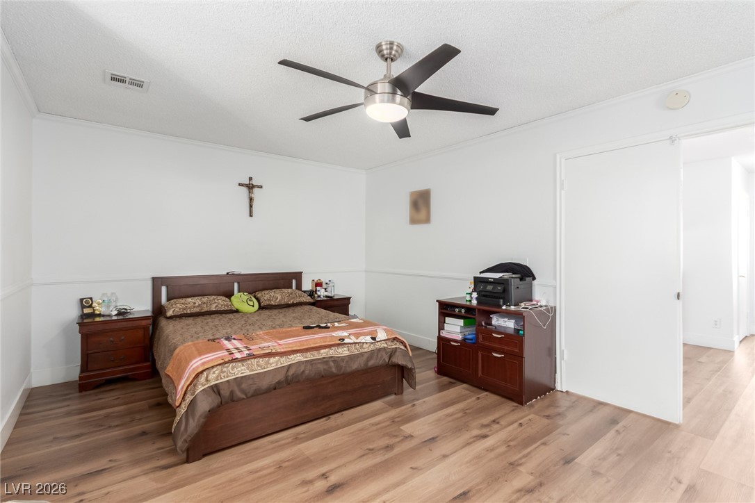 906 Ambusher Street Henderson, NV 89014 - Photo 14 of 38 Bedroom with light wood-style floors, a ceiling fan, crown molding, and a textured ceiling
