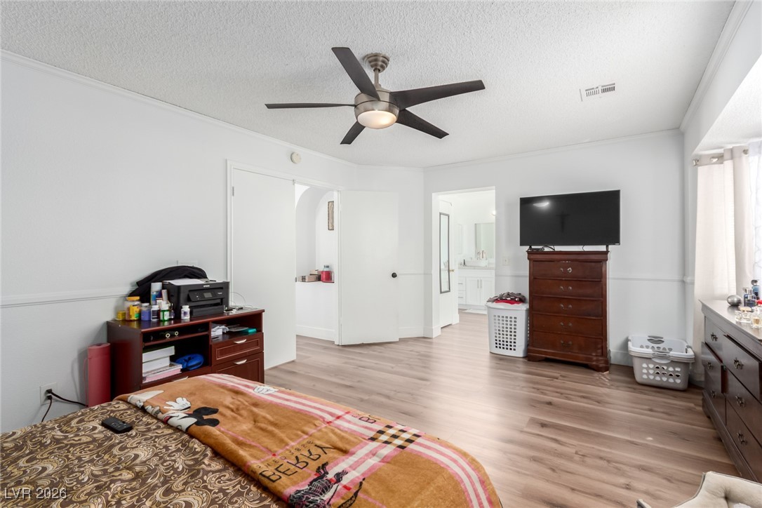 906 Ambusher Street Henderson, NV 89014 - Photo 15 of 38 Bedroom with light wood-type flooring, ceiling fan, crown molding, a textured ceiling, and ensuite bath