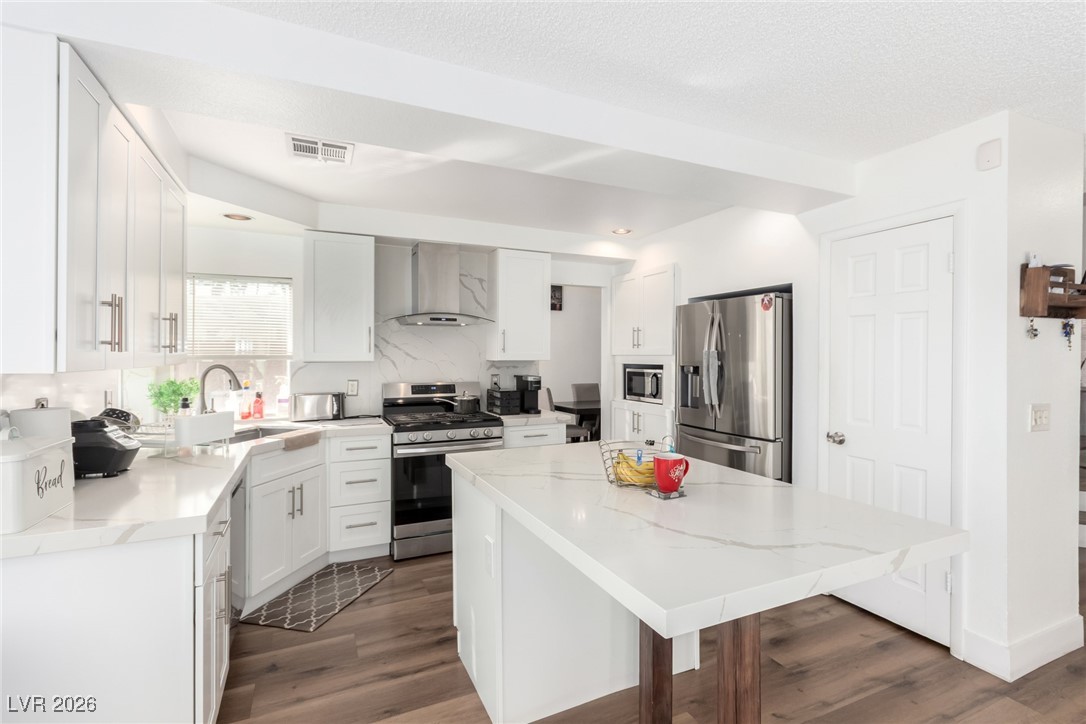 906 Ambusher Street Henderson, NV 89014 - Photo 2 of 38 Kitchen featuring white cabinets, stainless steel appliances, a center island, and dark wood finished floors