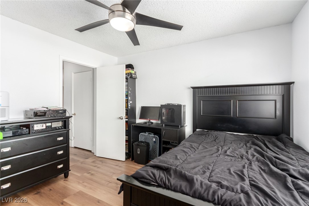 906 Ambusher Street Henderson, NV 89014 - Photo 22 of 38 Bedroom featuring wood finished floors, a textured ceiling, and a ceiling fan