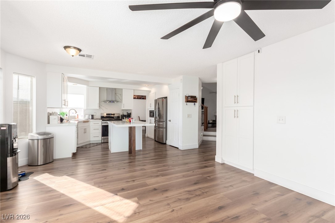 906 Ambusher Street Henderson, NV 89014 - Photo 9 of 38 Kitchen with white cabinetry, a center island, stainless steel appliances, light countertops, and dark wood-style flooring