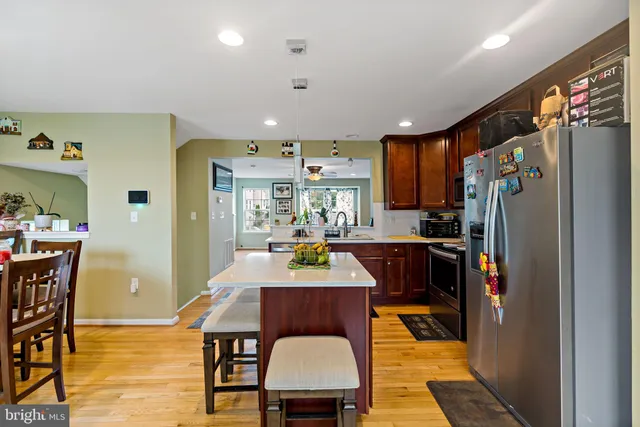 a dining room with stainless steel appliances granite countertop a refrigerator a stove a sink dishwasher and a dining table with wooden floor