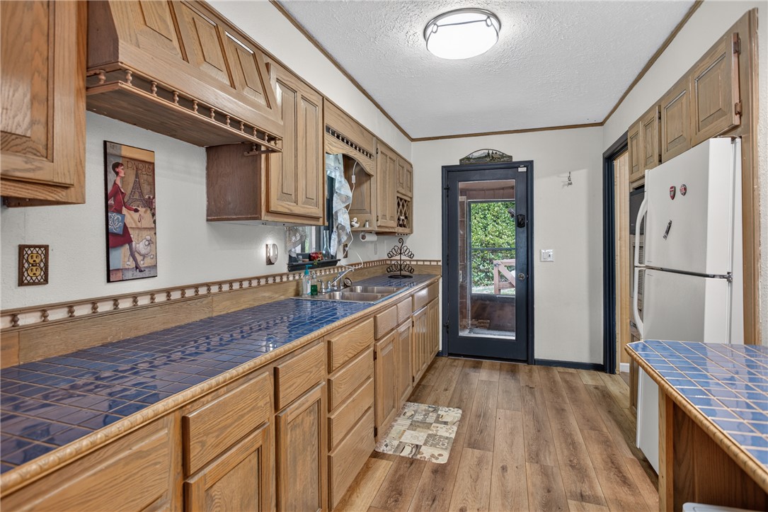351 River Road Westminster, SC 29693 - Photo 15 of 50 A well-equipped bar style kitchen features ample cabinetry, blue tile countertops, and durable laminate flooring.