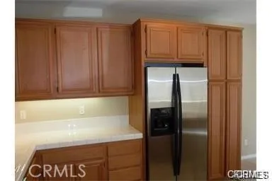 a close view of a refrigerator in kitchen with stainless steel appliances wooden cabinet