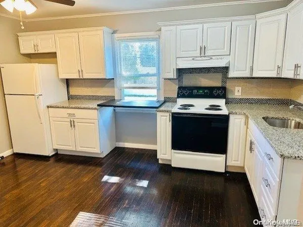a kitchen with stainless steel appliances granite countertop a stove a sink and white cabinets