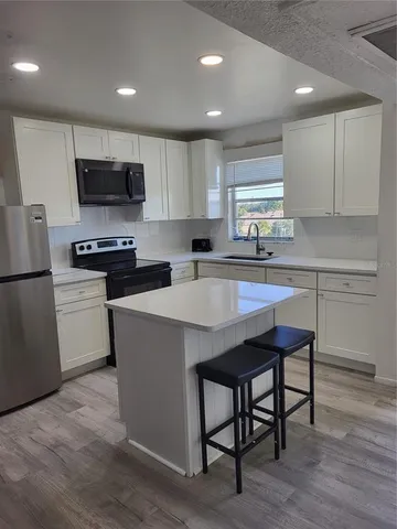 a kitchen with stainless steel appliances granite countertop a table chairs sink refrigerator and cabinets