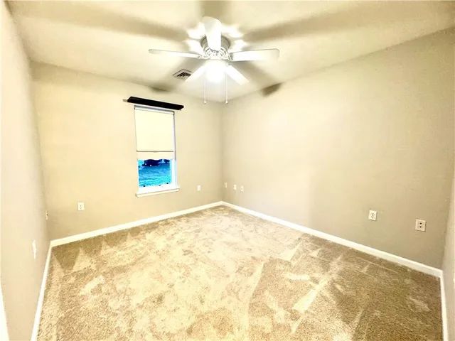 a view of a room with a ceiling fan and carpet