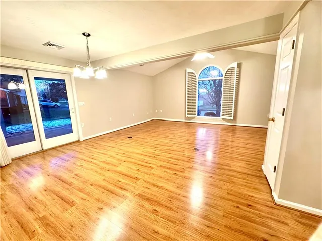 a view of an empty room with window and wooden floor