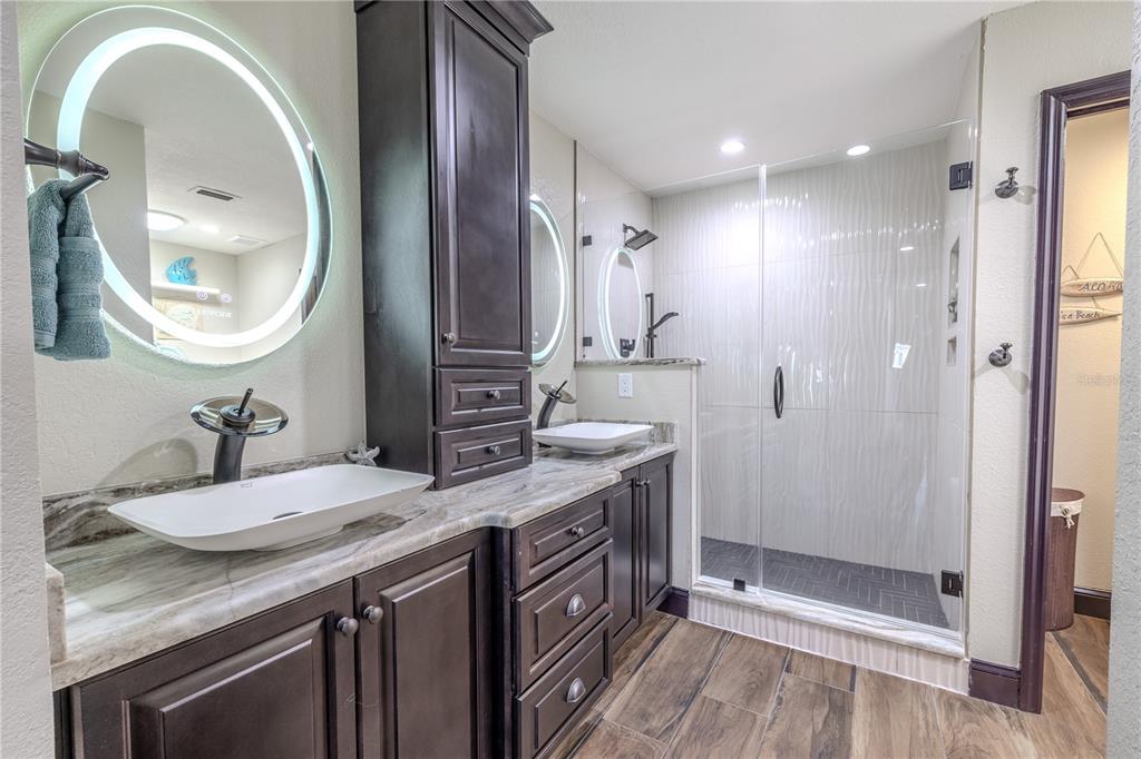 345 Boca Ciega Point Boulevard St. Petersburg, FL 33708 - Photo 6 of 64 a bathroom with a granite countertop double vanity sink a mirror and a shower