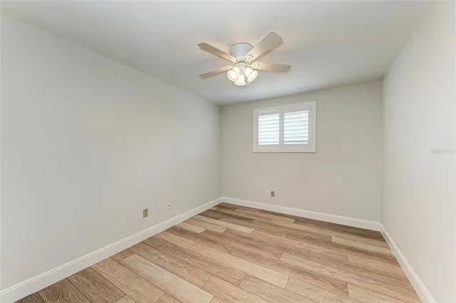 an empty room with a window and ceiling fan