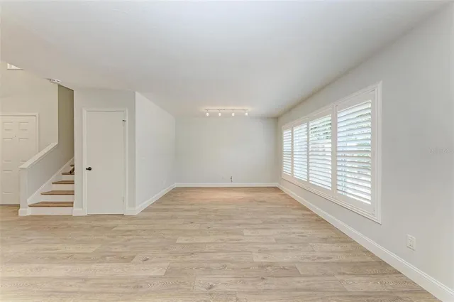 a view of an empty room with a window and wooden floor