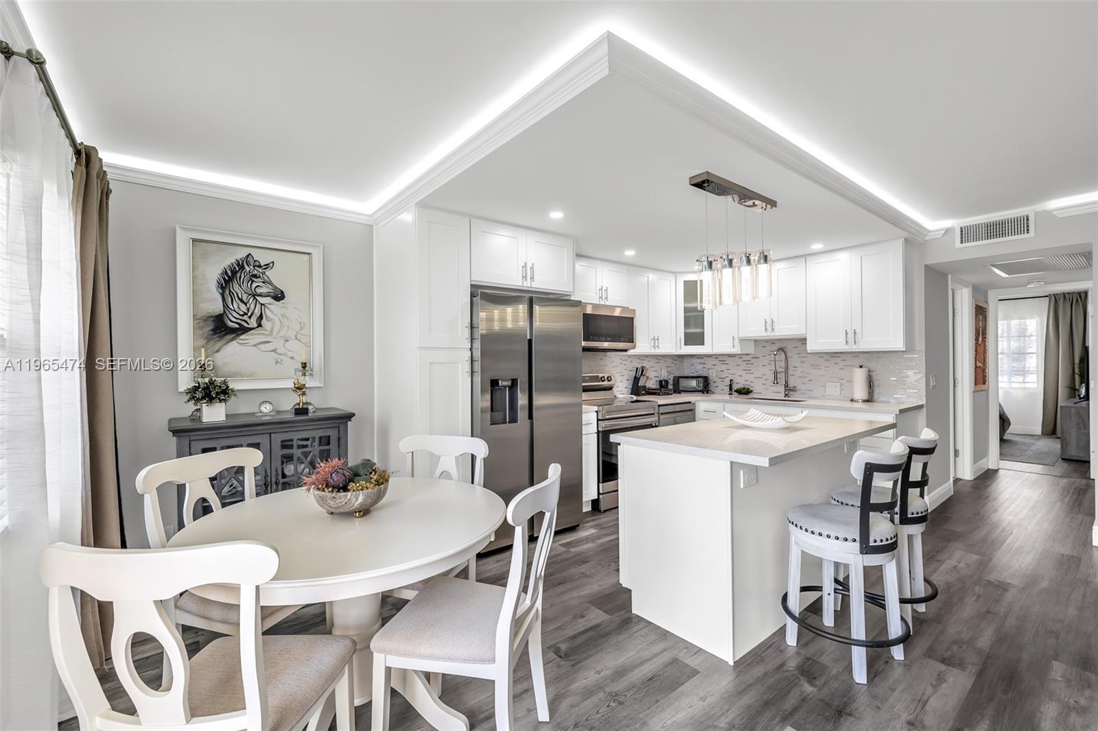 152 Dorset D, Unit 152 Boca Raton, FL 33434 - Photo 3 of 31 a kitchen with a dining table chairs refrigerator and wooden floor