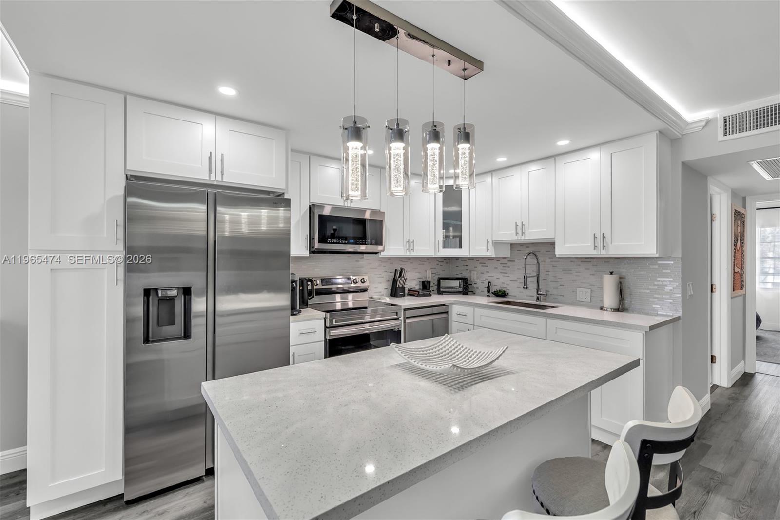 152 Dorset D, Unit 152 Boca Raton, FL 33434 - Photo 6 of 31 a kitchen with granite countertop a sink stainless steel appliances and white cabinets