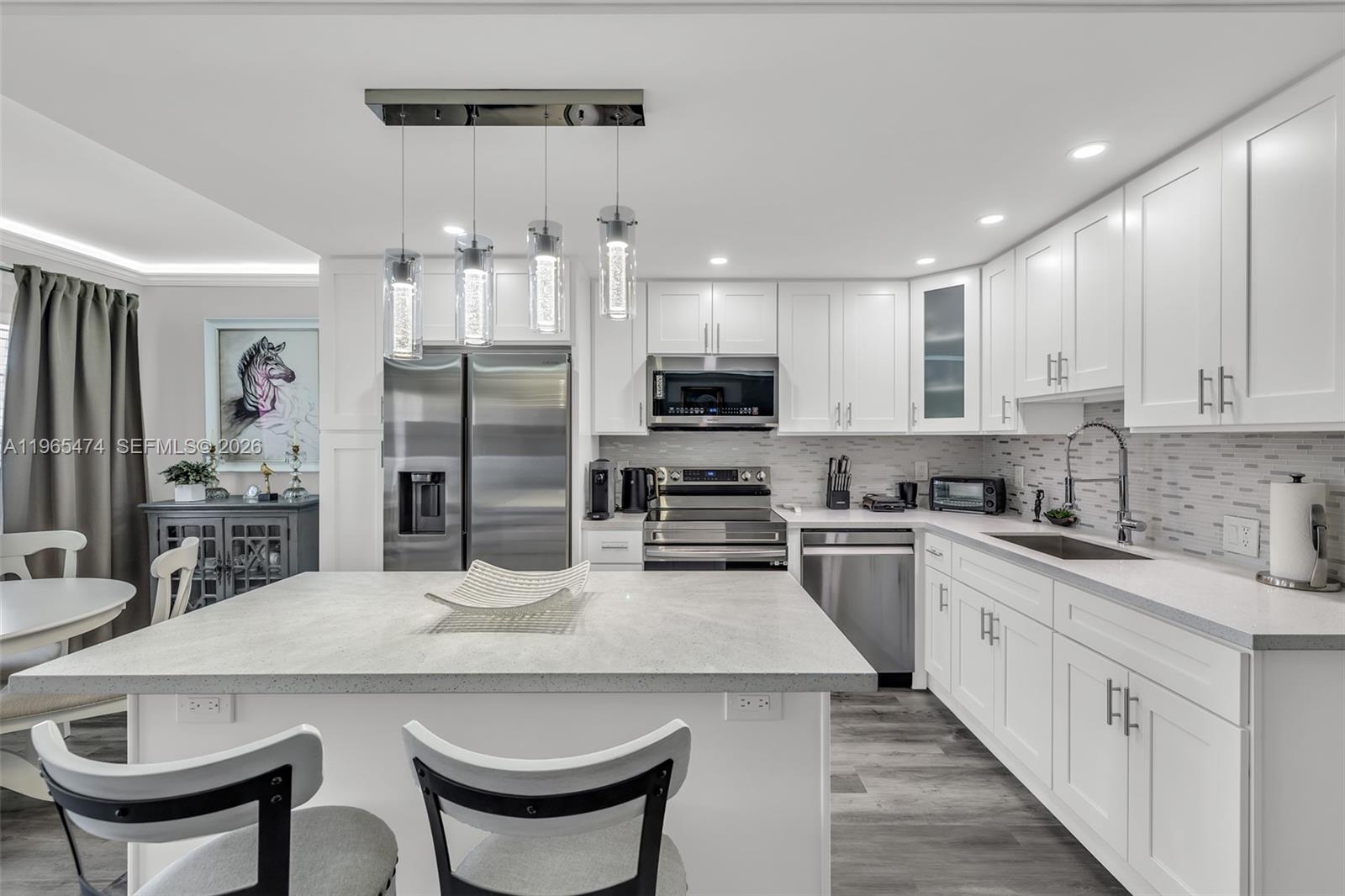 152 Dorset D, Unit 152 Boca Raton, FL 33434 - Photo 7 of 31 a kitchen with stainless steel appliances kitchen island granite countertop a kitchen island and chairs in it