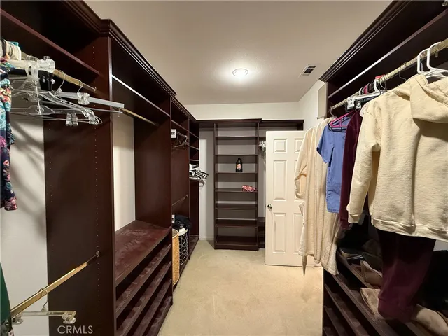 a view of walk in closet with clothes and shoes