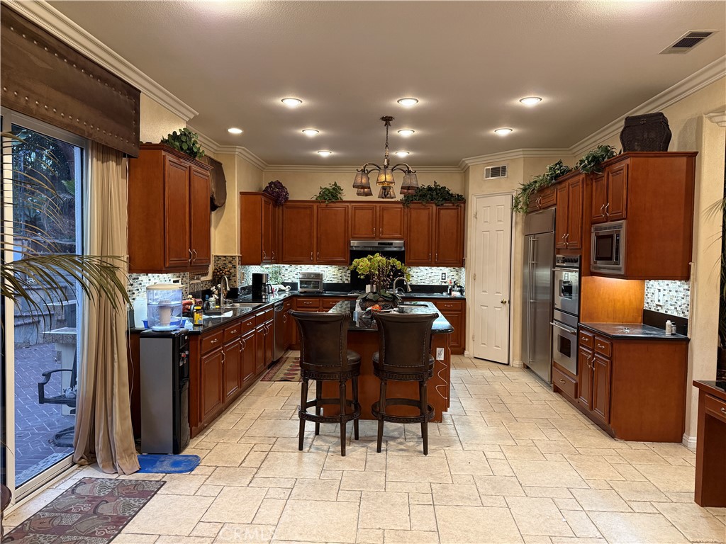 2119 Ridgeview Terrace Drive Signal Hill, CA 90755 - Photo 3 of 22 a kitchen with stainless steel appliances kitchen island granite countertop a table chairs and a refrigerator