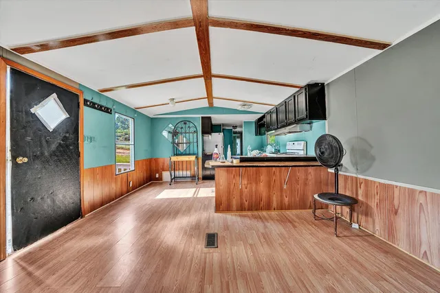an empty room with wooden floor fireplace and windows